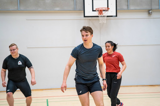 Three students run in the sports hall.